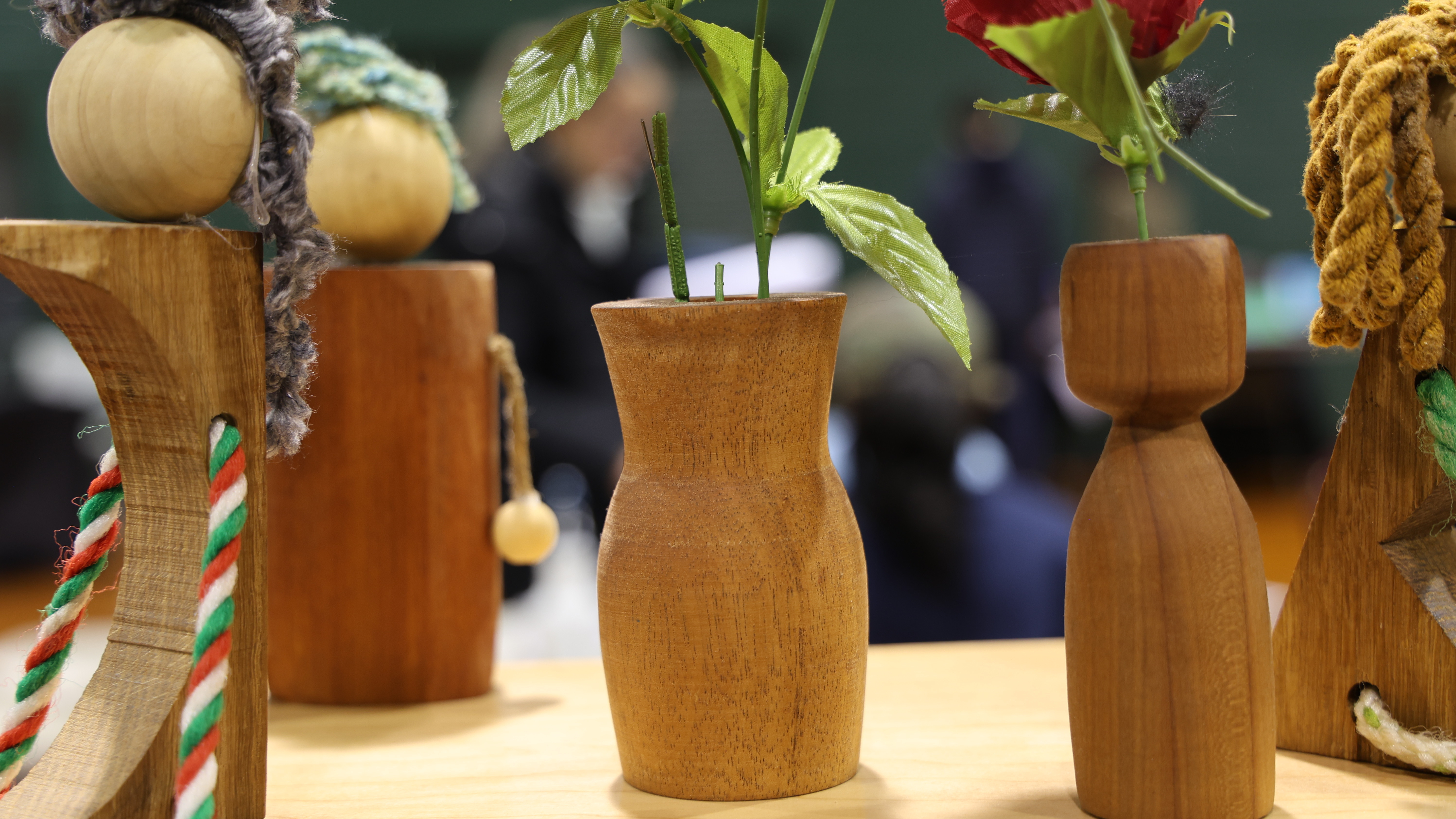Wooden decorative items: vases with artificial flowers, spheres, and braided ropes on a shelf.